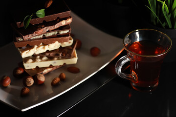 A bar of milk chocolate. Homemade milk chocolate with almonds and dried strawberries. Pieces of milk chocolate. Set of milk chocolate with tea.