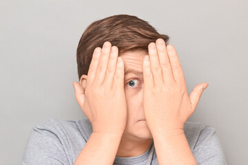 Portrait of curious man looking through gap between hands