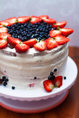 chocolate cake with white cream, strawberries and blueberries