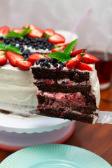 chocolate cake with white cream, strawberries and blueberries