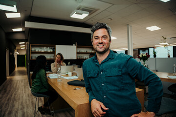 Fototapeta premium Portrait of smiling caucasian business man sitting against office table enjoying lunch break 