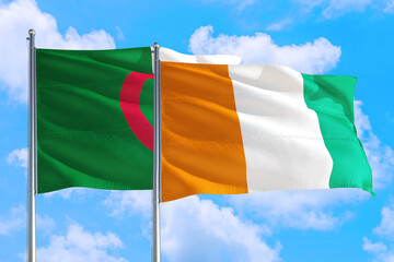 Cote D'Ivoire and Algeria national flag waving in the windy deep blue sky. Diplomacy and international relations concept.