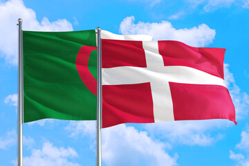 Fototapeta na wymiar Denmark and Algeria national flag waving in the windy deep blue sky. Diplomacy and international relations concept.