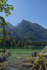 Berchtesgaden lake Hintersee with trees in foreground and mountains in the background on a summer day