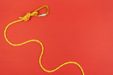 Overhand knot with orange carabiner and yellow climbing rope on red background