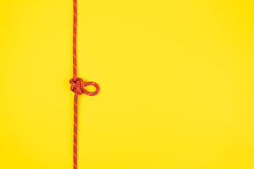 Fototapeta na wymiar Butterfly loop knot with red climbing rope on yellow background