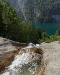 Berchtesgaden lake K&ouml;nigssee with trees in foreground and mountains in the background with waterstream