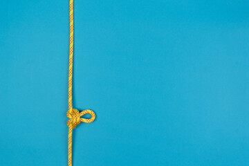Butterfly loop knot with yellow climbing rope on blue background