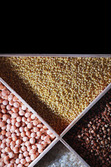 A set of grain cereals. Rice, buckwheat and millet groats in a wooden tray. A grocery set of cereals. Import of grain.