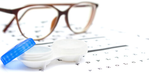 Contact lenses case and eye glasses on and eye test chart. Vision concept. Way to improve vision