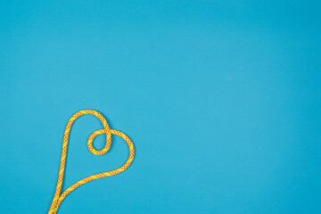 Yellow heart with climbing rope on blue background