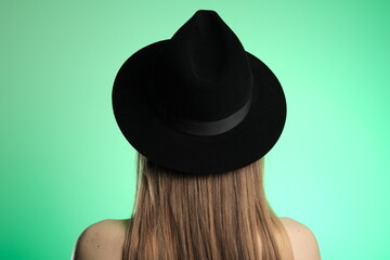 A woman in a black hat on a green background