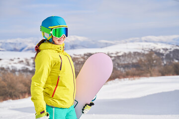 Fototapeta na wymiar Woman with snowboard against background of mountains