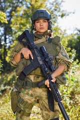 portrait of confident military woman with a gun in forest, hunter female in camouflage suit with a gun stand in nature alone