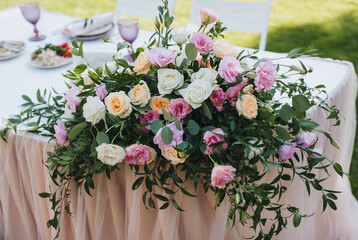 A large bouquet of multi-colored roses lies on the table with a tablecloth. Wedding decorations close-up.