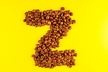 Latin alphabet letters made with coffee beans on yellow background