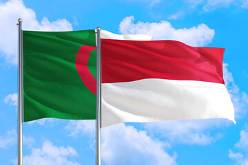Monaco and Algeria national flag waving in the windy deep blue sky. Diplomacy and international relations concept.