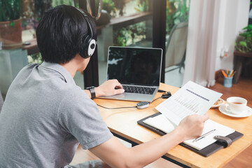 Businessman video call with clients on laptop in home office. Man wear headphone video calling or distance education e-leaning online course.