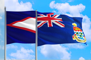 Cayman Islands and American Samoa national flag waving in the windy deep blue sky. Diplomacy and international relations concept.