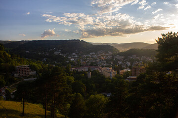 View from the mountain to the city park and houses with sunbeams