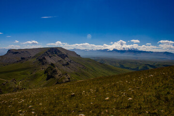 An excellent view from the plateau to the extinct volcano and the snowy peak of Mount Elbrus. Below is a green gorge