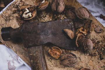 Old rusty axe with cracked walnuts on the table, toned. Seasoning cuisine. Walnuts with shell and old axe. Rural still life. Nuts concept. Autumn details. Organic healthy food. 