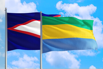 Gabon and American Samoa national flag waving in the windy deep blue sky. Diplomacy and...