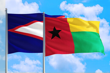 Guinea and American Samoa national flag waving in the windy deep blue sky. Diplomacy and...