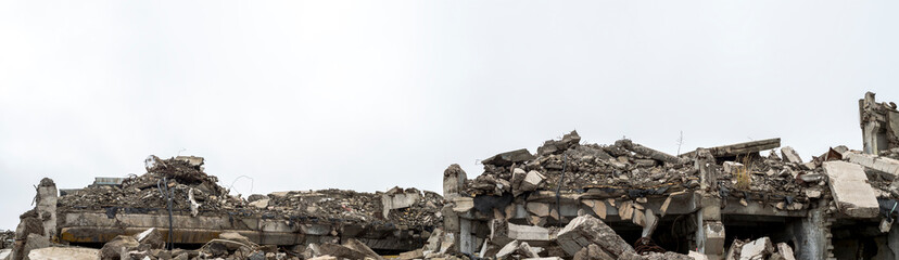 Panorama of the remains of a destroyed building, piles of concrete debris and construction debris. Background.