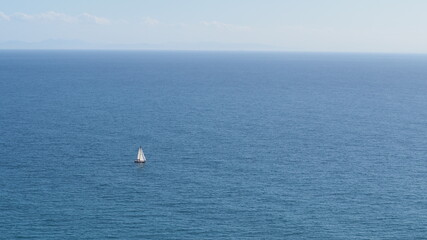 Obraz premium Sailboat sailing alone and in the distance in the middle of the sea on a sunny day