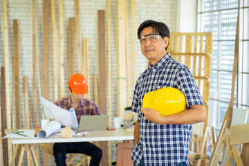 professional Asian Engineer with protective hard hat safety work in workshop wood plank...