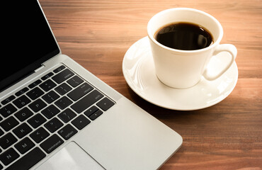 Obraz na płótnie Canvas Laptop with cup of coffee on old wooden table.