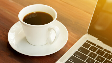 Laptop with cup of coffee on old wooden table.