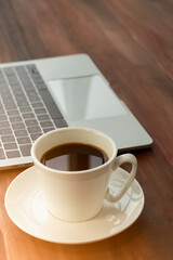 Coffee served in a cup, placed beside a portable computer