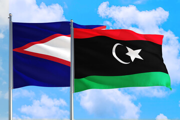 Libya and American Samoa national flag waving in the windy deep blue sky. Diplomacy and...