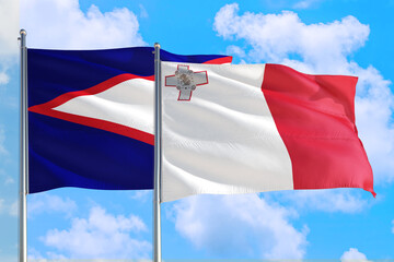 Fototapeta na wymiar Malta and American Samoa national flag waving in the windy deep blue sky. Diplomacy and international relations concept.