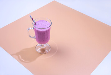 a glass of BlackBerry smoothie on a colored background
