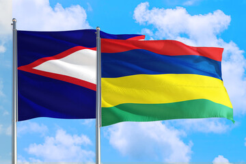 Mauritius and American Samoa national flag waving in the windy deep blue sky. Diplomacy and...