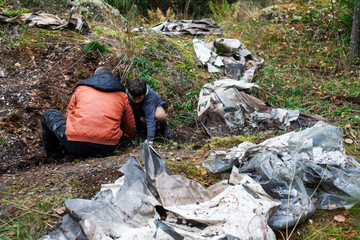 big amount of trash in forest, family father and son picking garbage away, global environment issues