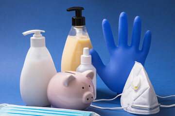 Piggy bank and various personal protective equipment on the table. Concept on spending on hygiene products during the coronavirus pandemic