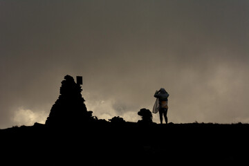 Couple of tourists in the clouds on top of Mount Brebeneskul, tourists standing on top in the raincoats, gloomy weather.