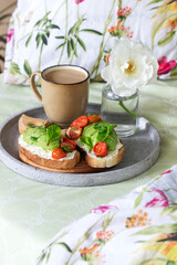 Breakfast of sandwiches with cottage cheese, avocado and tomatoes and coffee, served in bed.