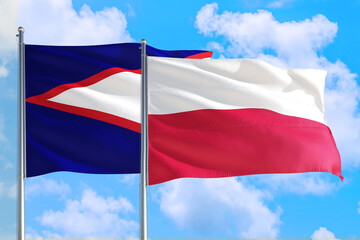 Poland and American Samoa national flag waving in the windy deep blue sky. Diplomacy and international relations concept.