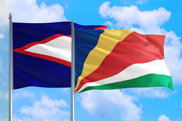 Seychelles and American Samoa national flag waving in the windy deep blue sky. Diplomacy and international relations concept.