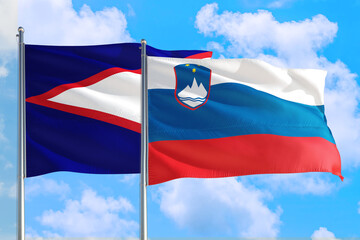 Slovenia and American Samoa national flag waving in the windy deep blue sky. Diplomacy and international relations concept.