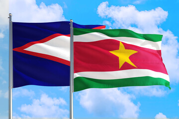 Suriname and American Samoa national flag waving in the windy deep blue sky. Diplomacy and international relations concept.