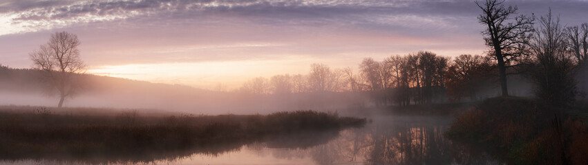 Banner panoramic autumn landscape fog over river and sky with rising sun