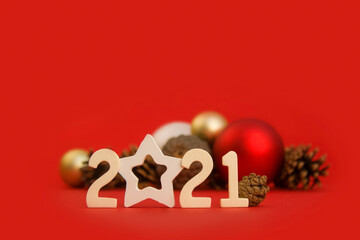 Christmas card with 2021 numbers, new year balls, fir cones on a red background. The basis for a...