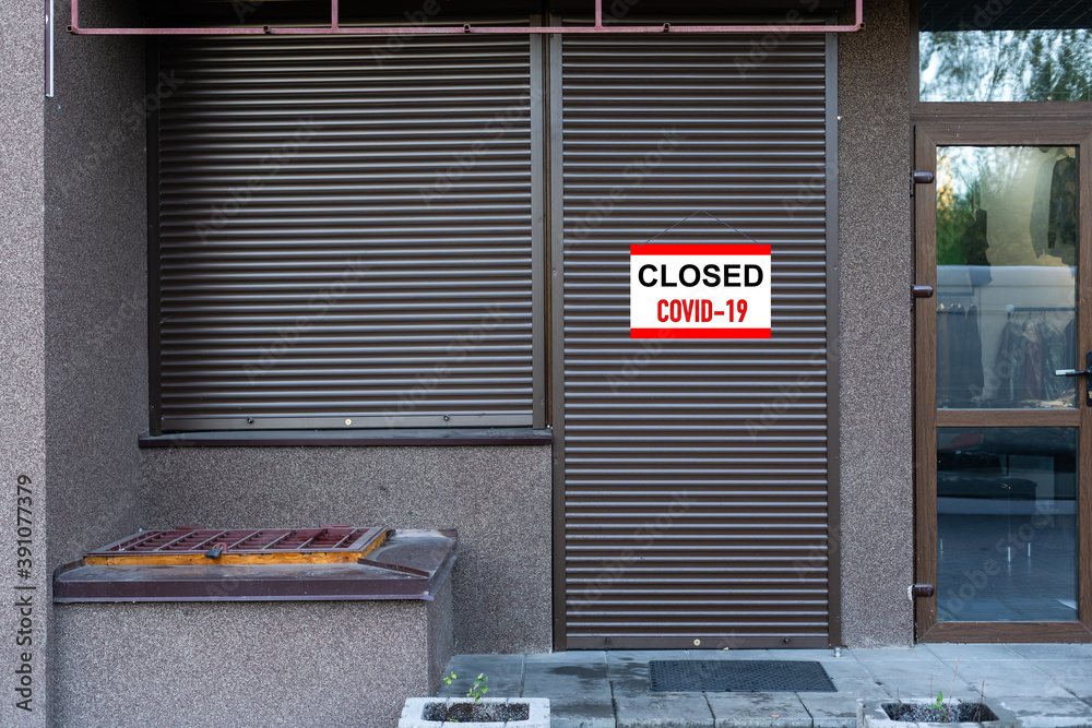 Poster close-up on a red closed sign in the window of a shop displaying the message 