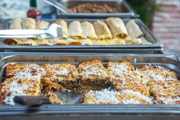Baked potatoes with minced meat sprinkled with coconut shavings in a tray. Moussaka with fried crust